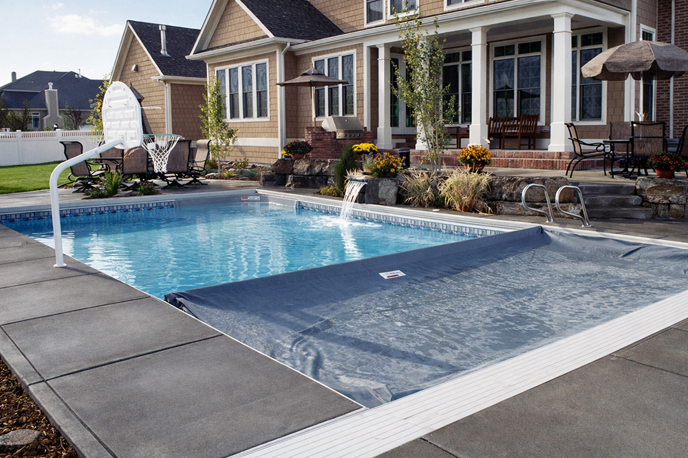 Concrete pool deck with automatic cover in a Minnesota backyard